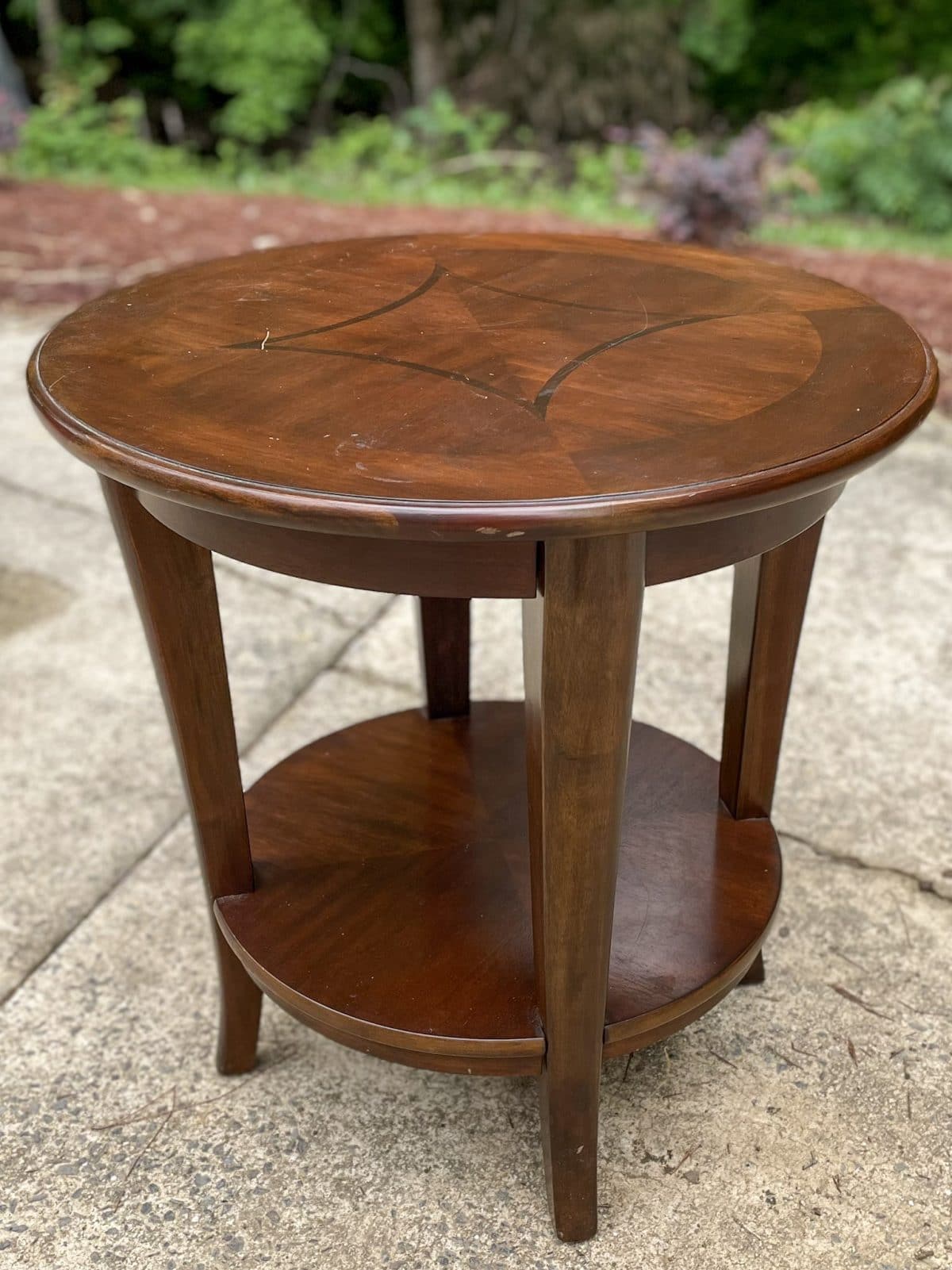 round cherry end table sitting in driveway