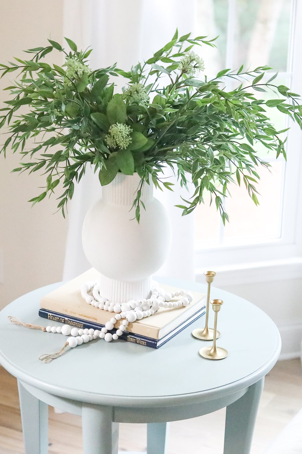 styling an end table with books, candle ticks, and a vase